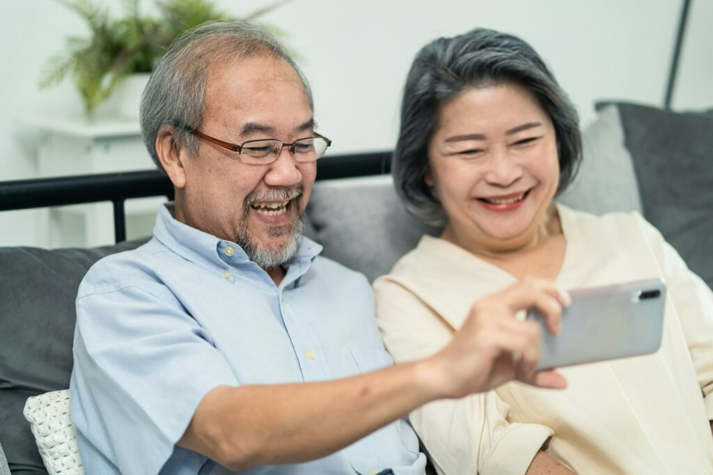 Asian old woman and old man hold mobile phone talking and smiling on video call with family